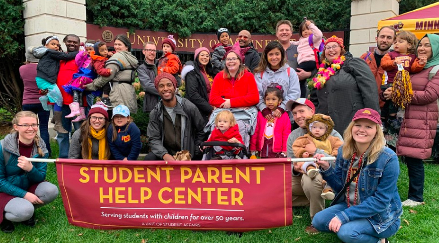 group of students with their children of varying ages holding a sign that says student parent help center