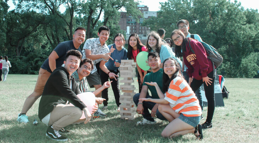group of asian students smiling and playing jenga together outside