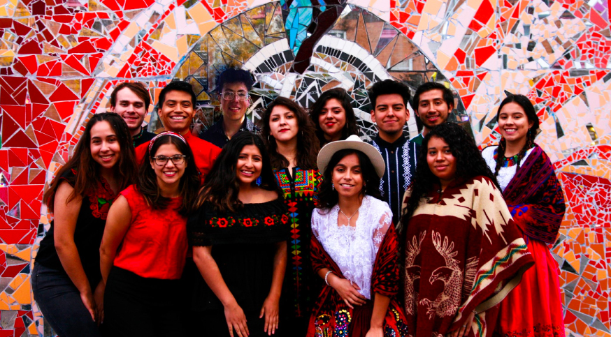 group of latinx students smiling in front of a red colored mosaic wall